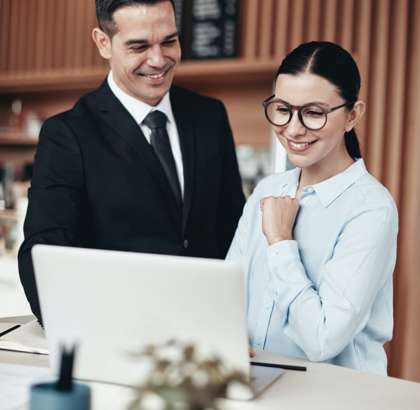 two-smiling-businesspeople-using-a-laptop-together-in-an-office.jpg